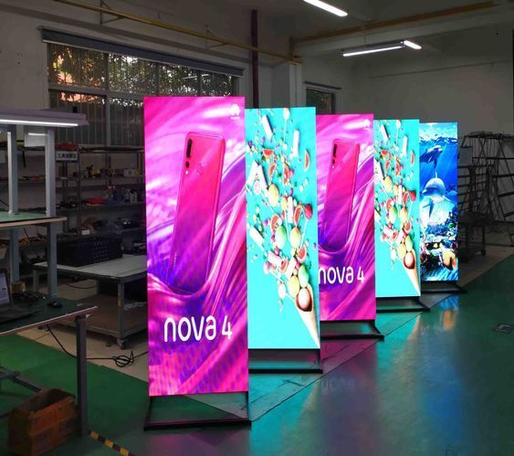 Totens de LED exibindo campanha de celular e frutas em uma fábrica